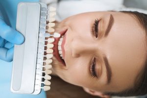 Dentist matching veneer color to patient's teeth to eliminate tooth erosion 