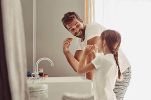 Father and daughter brushing their teeth to get rid of bad breath